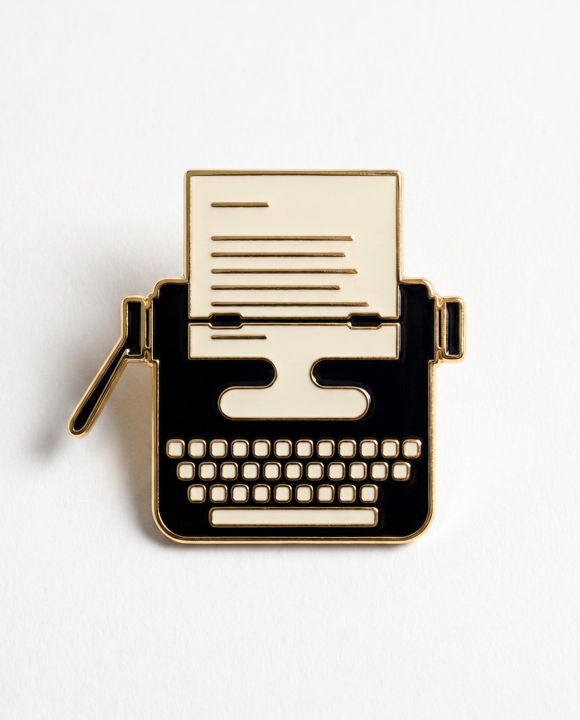 The Highlighter Pin — hard enamel typewriter with paper-cream face, black body, gold trim